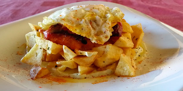 Huevos rotos con pimientos de piquillos rellenos de chorizo y rulo de cabra , uno de los platos de otoño del restaurante El Lagartijo